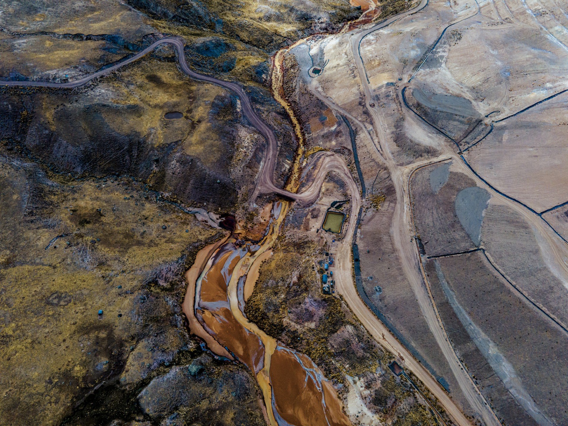 Toma aérea de ramificaciones de un río seco sobre tierra rojiza.
