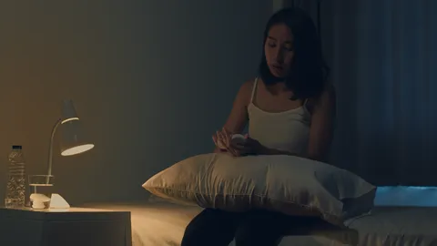 beautiful-asian-young-woman-sitting-on-bed-take-sleeping-pill-or-night-medicine-in-bedroom-unhealthy-sick-indian-female-suffers-from-insomnia-or-headache-depressed-girl-holds-antidepressant-meds