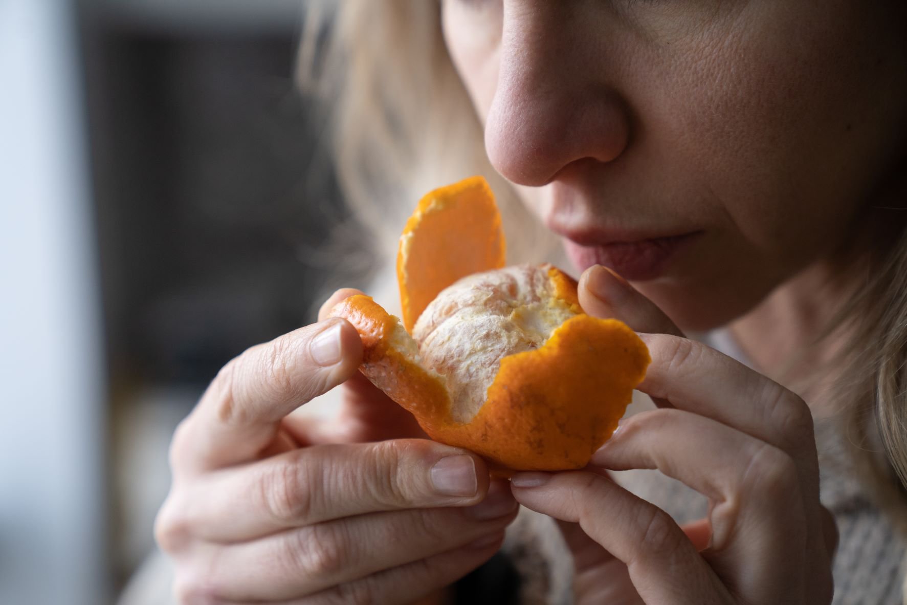 sick-woman-trying-to-sense-smell-of-fresh-tangerine-orange-has-symptoms-of-covid-19-corona-virus.jpg