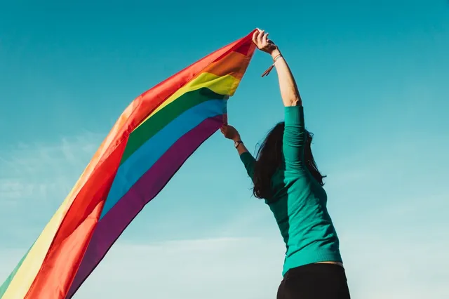 unrecognizable_young_girl_raising_gay_pride_flag_above_her_head.jpg